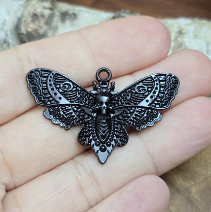 Das Bild zeigt einen Anhänger mit schwarzer Beschichtung. Mit 27 mm Breite und einer stabilen Öse eignet er sich perfekt für Ketten, Choker und andere individuelle Schmuckstücke.