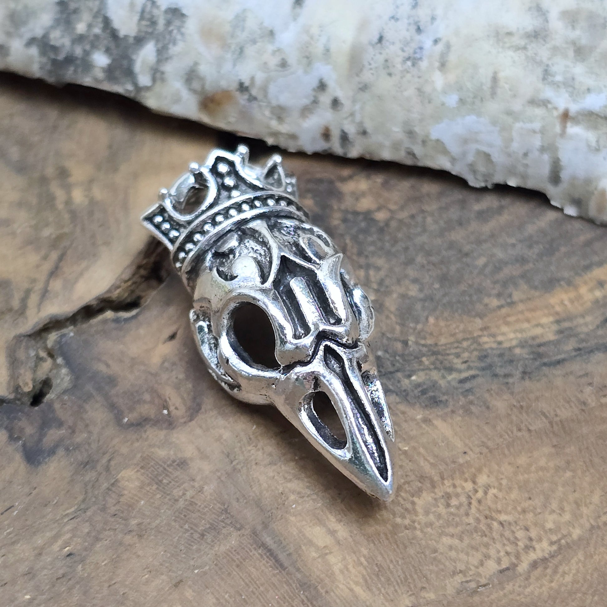 Das Bild zeigt einen Anhänger Krähenschädel, Rabenschädel &nbsp;mit Krone, antik silberfarbig, 33mm

... für einen mystischen und zeitlosen Look.

Der Anhänger hat oben am Schädel eine feste Öse und eignet sich hervorragend für die individuelle Schmuckherstellung.