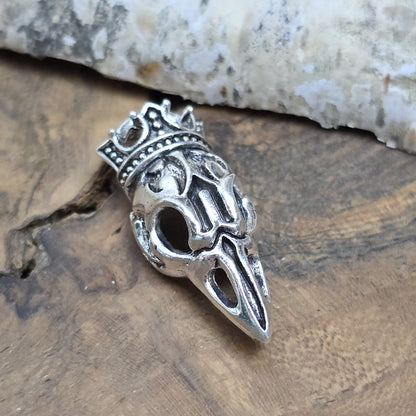 Das Bild zeigt einen Anhänger Krähenschädel, Rabenschädel &nbsp;mit Krone, antik silberfarbig, 33mm

... für einen mystischen und zeitlosen Look.

Der Anhänger hat oben am Schädel eine feste Öse und eignet sich hervorragend für die individuelle Schmuckherstellung.
