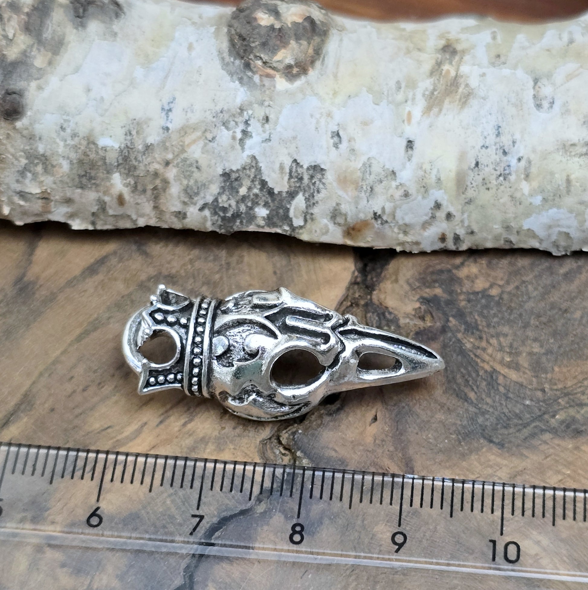Das Bild zeigt einen Anhänger Krähenschädel, Rabenschädel mit Krone, antik silberfarbig, 33mm

... für einen mystischen und zeitlosen Look.

Der Anhänger hat oben am Schädel eine feste Öse und eignet sich hervorragend für die individuelle Schmuckherstellung.