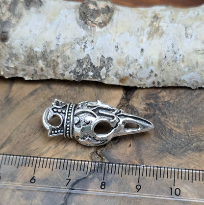 Das Bild zeigt einen Anhänger Krähenschädel, Rabenschädel mit Krone, antik silberfarbig, 33mm

... für einen mystischen und zeitlosen Look.

Der Anhänger hat oben am Schädel eine feste Öse und eignet sich hervorragend für die individuelle Schmuckherstellung.