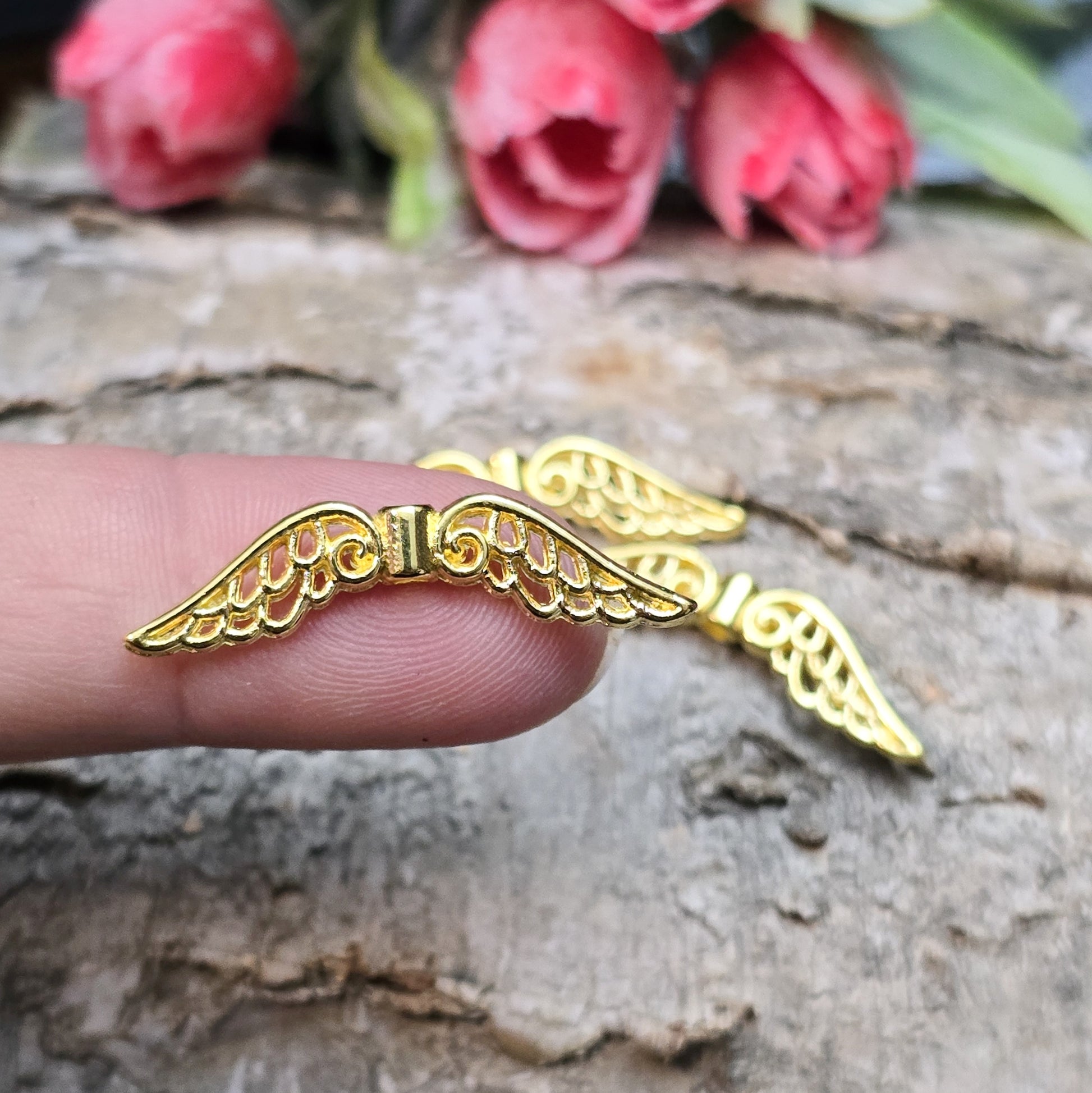 Das Bild zeigt mehrere vergoldete Flügelperlen aus Metall, jeweils 30 mm breit. Die Flügel sind filigran gestaltet, mit geschwungenen Linien und feinen Details. Sie eignen sich ideal zur Herstellung von Schutzengeln für Schmuck, Schlüsselanhänger oder Dekorationen. Die glänzende Goldfarbe verleiht ihnen eine edle und elegante Optik.