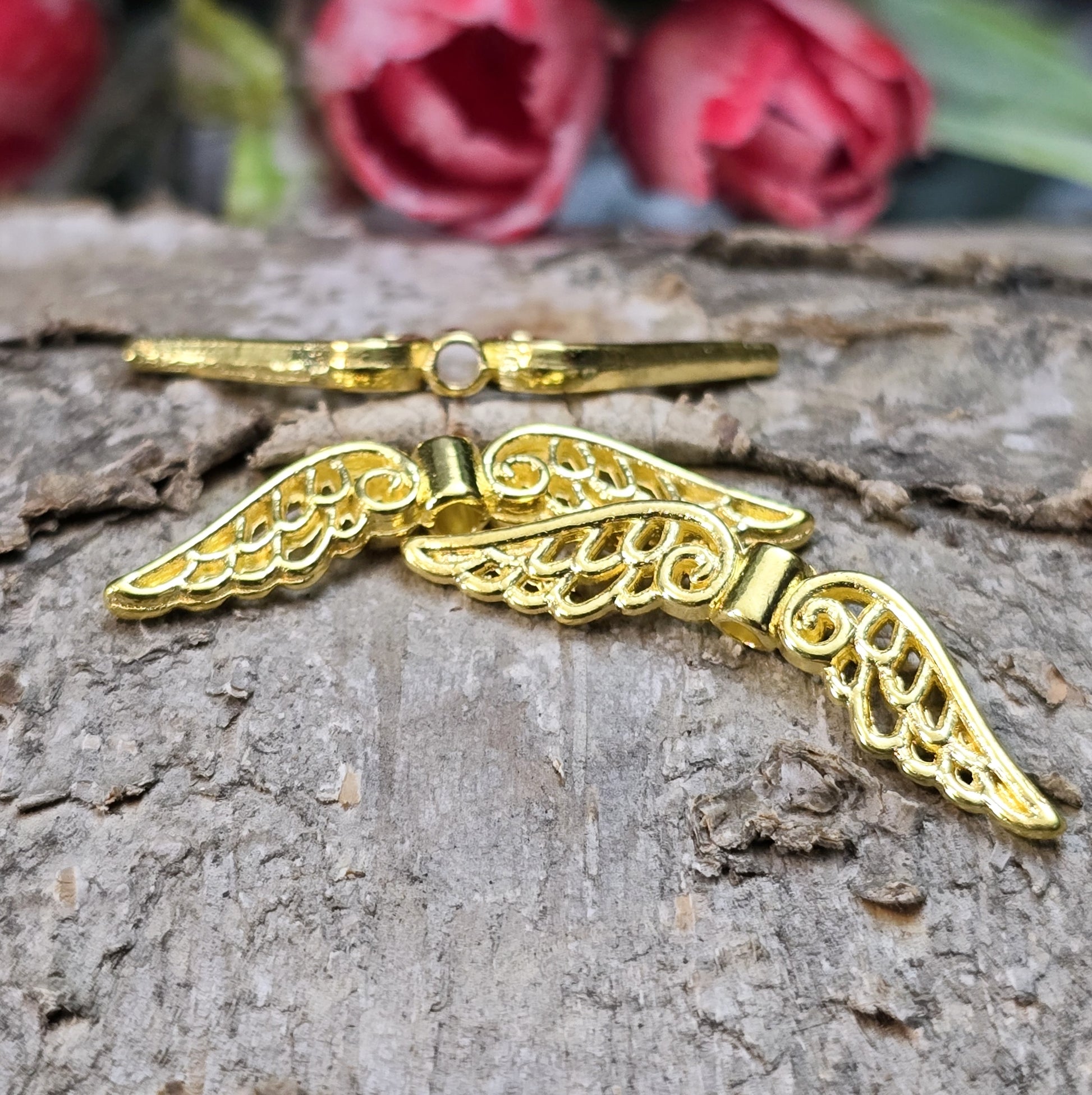 Das Bild zeigt mehrere vergoldete Flügelperlen aus Metall, jeweils 30 mm breit. Die Flügel sind filigran gestaltet, mit geschwungenen Linien und feinen Details. Sie eignen sich ideal zur Herstellung von Schutzengeln für Schmuck, Schlüsselanhänger oder Dekorationen. Die glänzende Goldfarbe verleiht ihnen eine edle und elegante Optik.