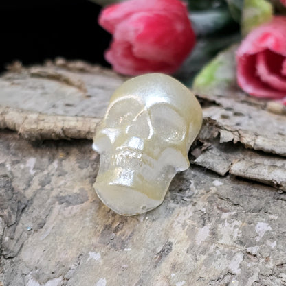 Das Bild zeigt einen Cabochon aus Resin mit cremeweißer Farbe auf einem Stück Birke.