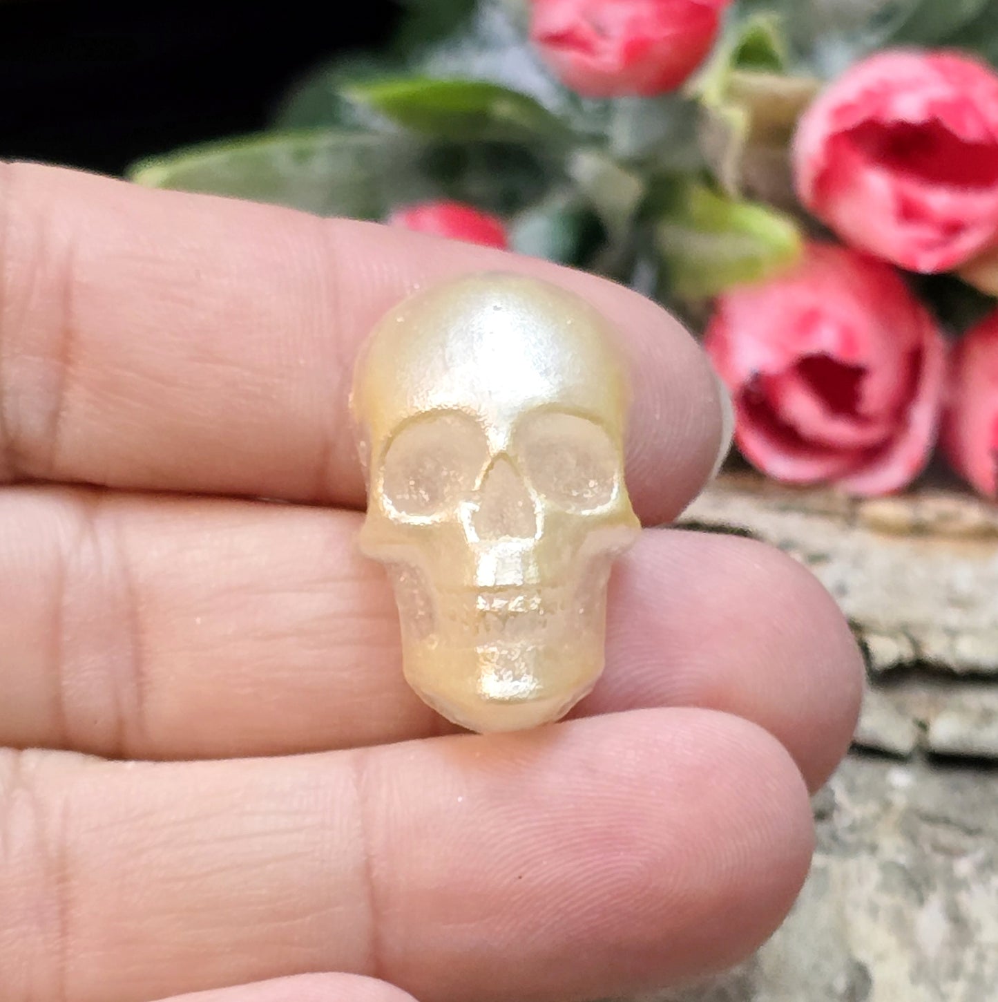Das Bild zeigt einen Cabochon aus Resin mit cremeweißer Farbe auf einem Stück Birke.