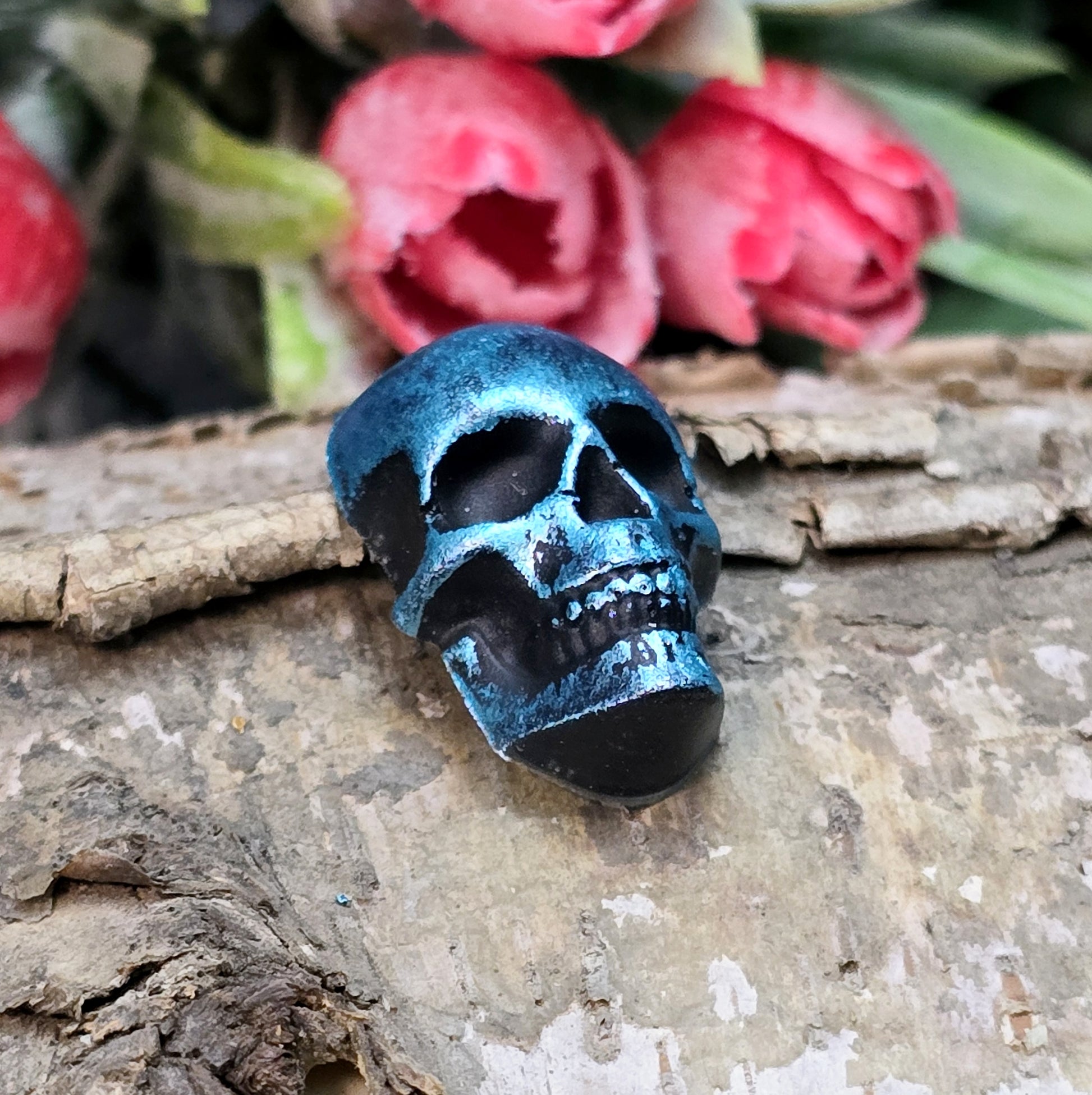 Das Bild zeigt einen Totenkopf-Cabochon in Schwarz mit türkisfarbener Wachsverzierung