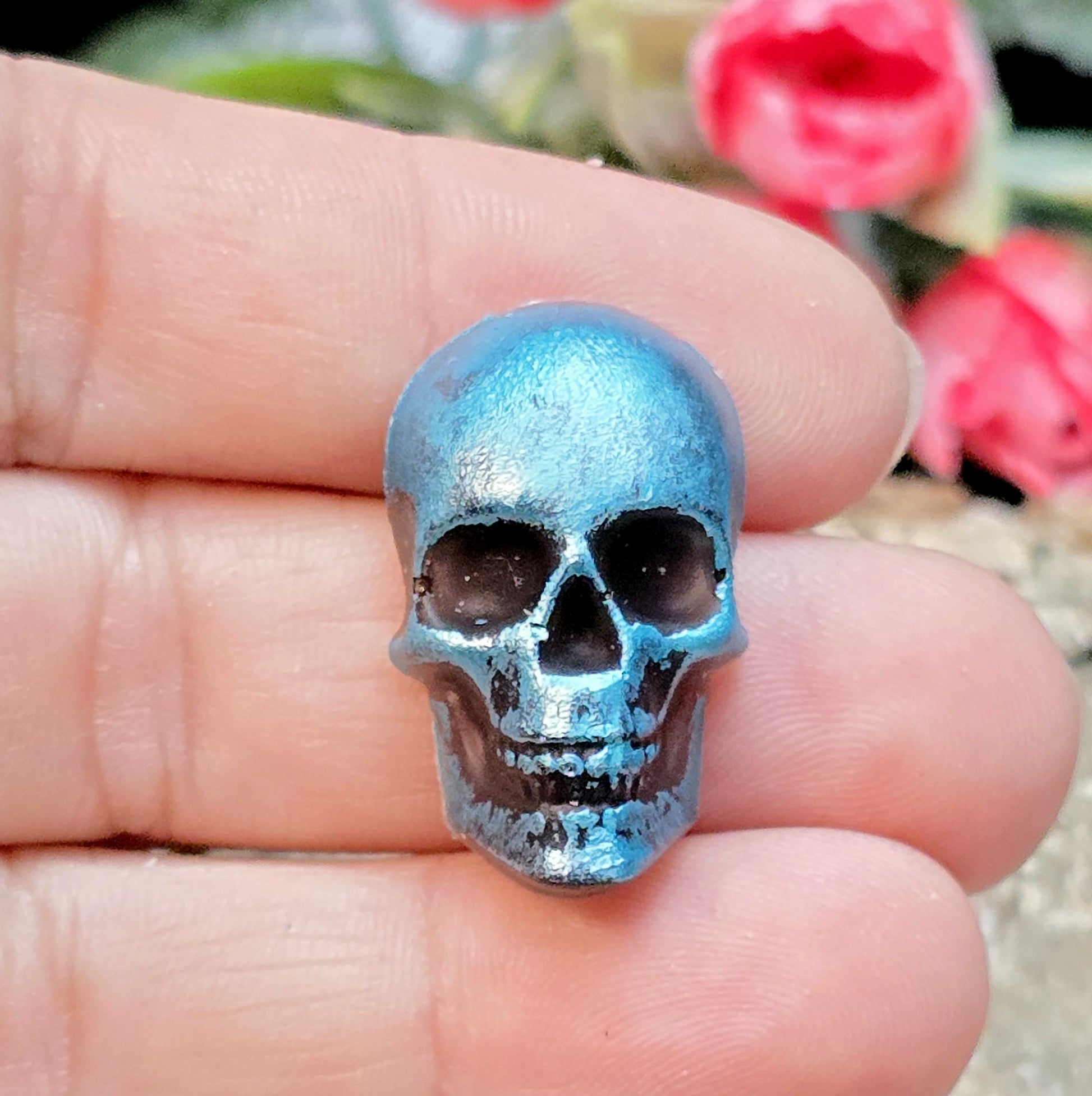 Das Bild zeigt einen Totenkopf-Cabochon in Schwarz mit türkisfarbener Wachsverzierung
