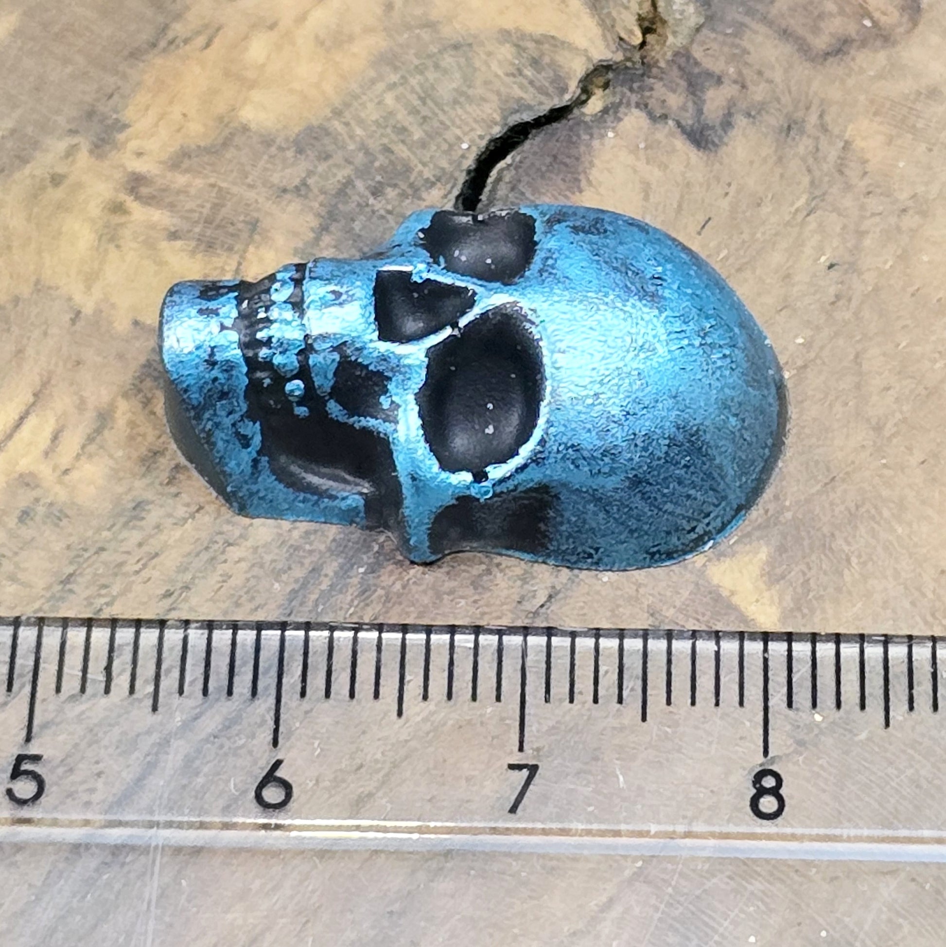 Das Bild zeigt einen Totenkopf-Cabochon in Schwarz mit türkisfarbener Wachsverzierung