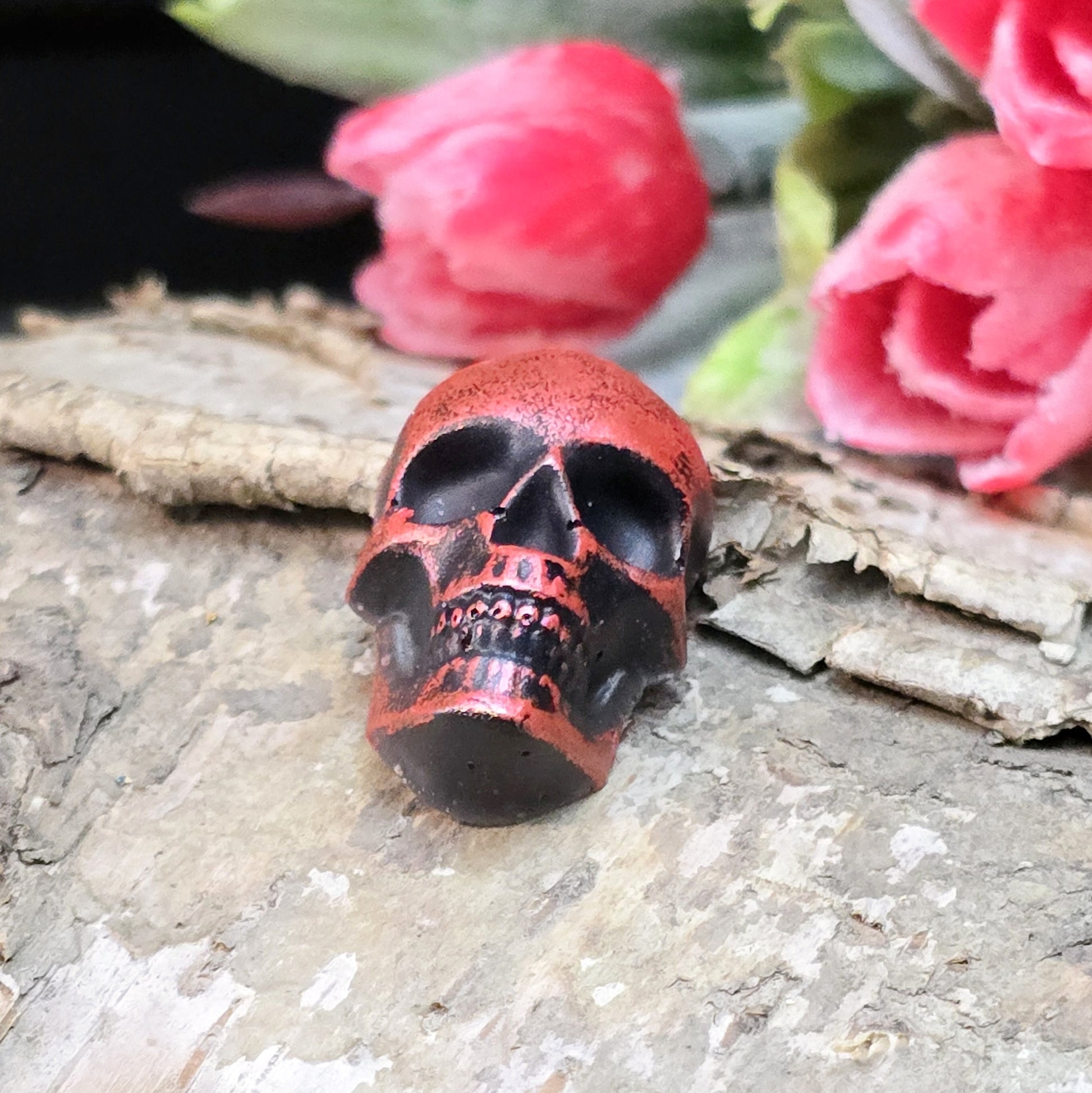 Das Bild zeigt einen Totenkopf-Cabochon in Schwarz mit roter Wachsverzierung