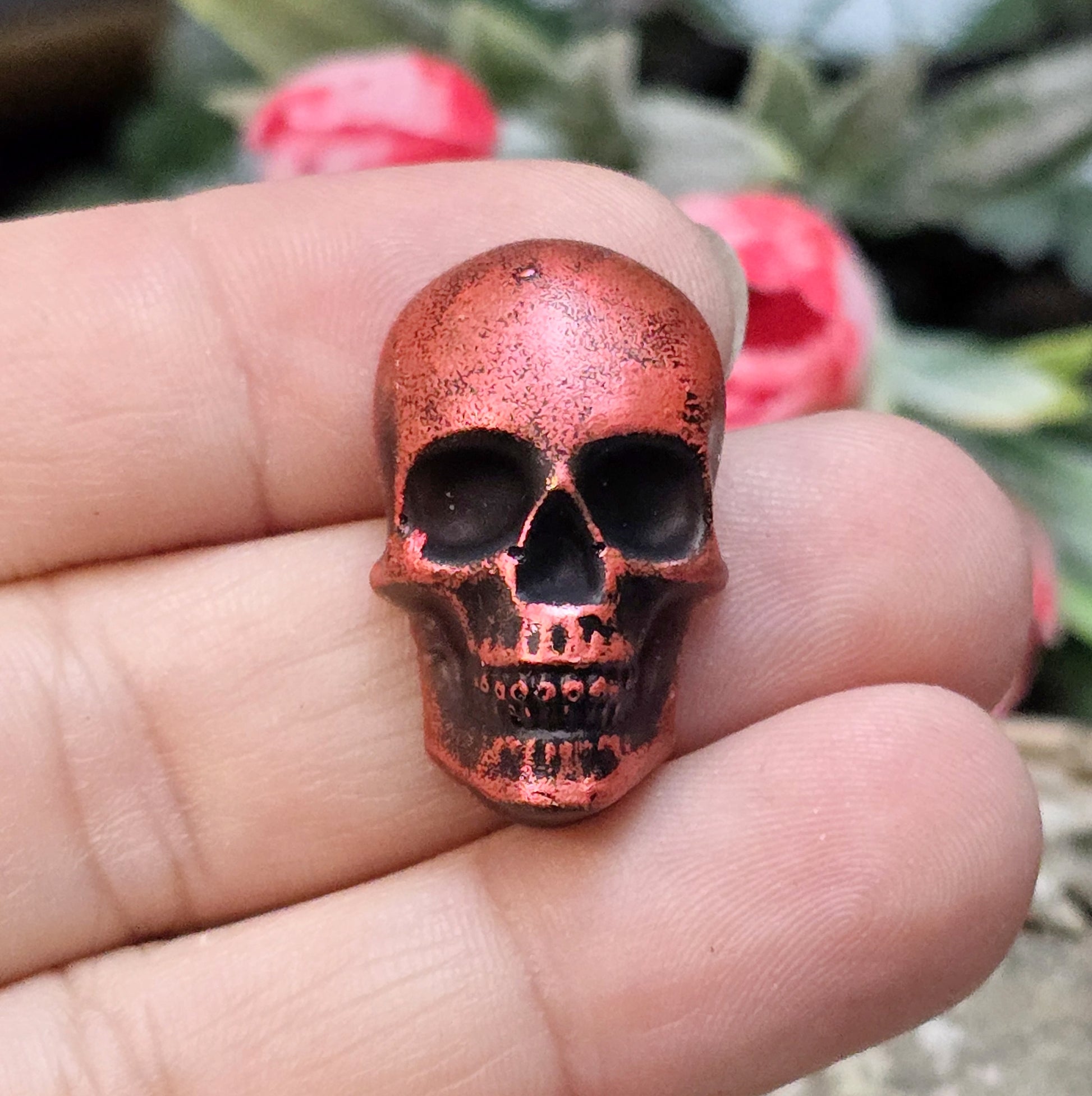 Das Bild zeigt einen Totenkopf-Cabochon in Schwarz mit roter Wachsverzierung