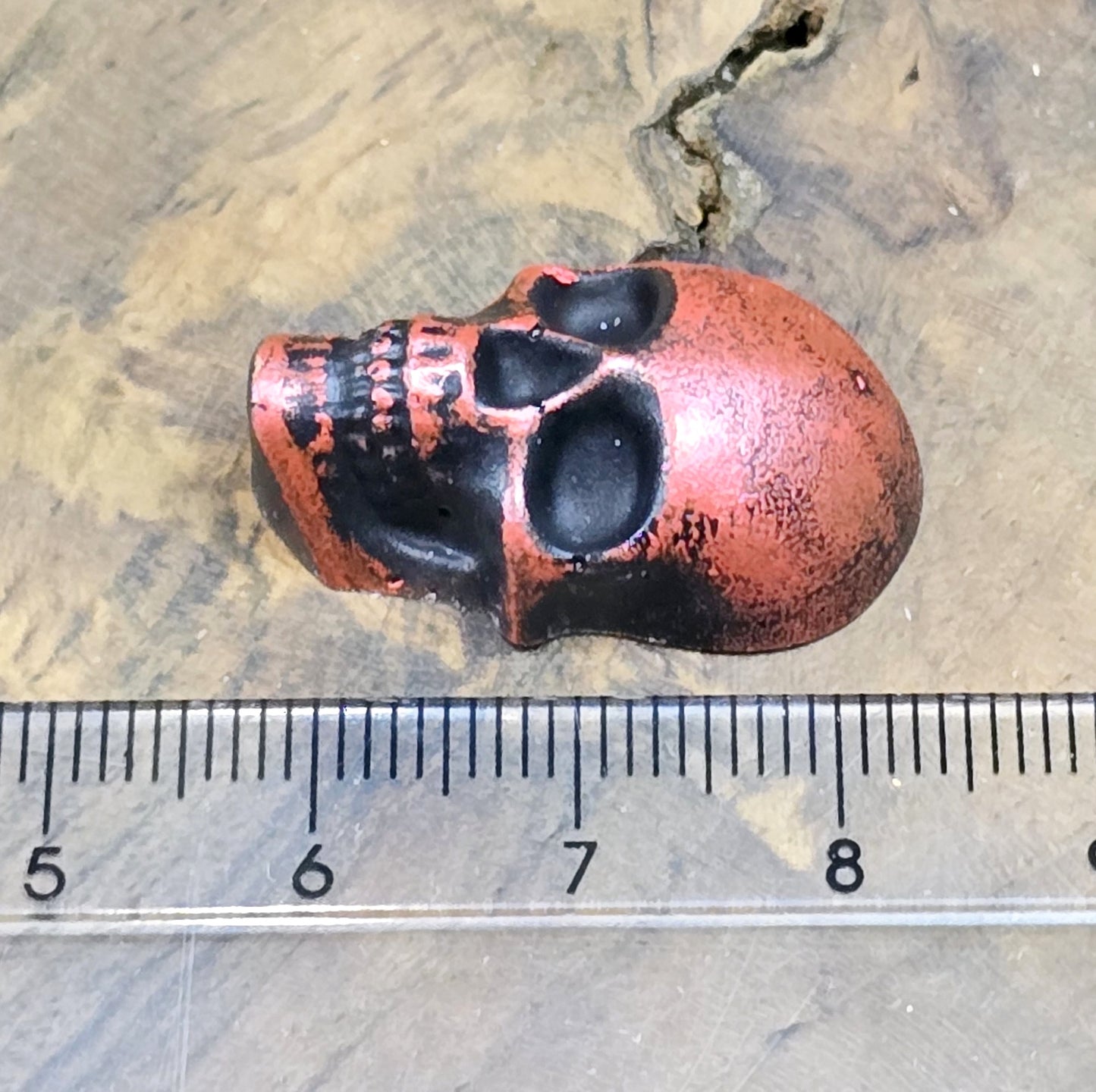 Das Bild zeigt einen Totenkopf-Cabochon in Schwarz mit roter Wachsverzierung