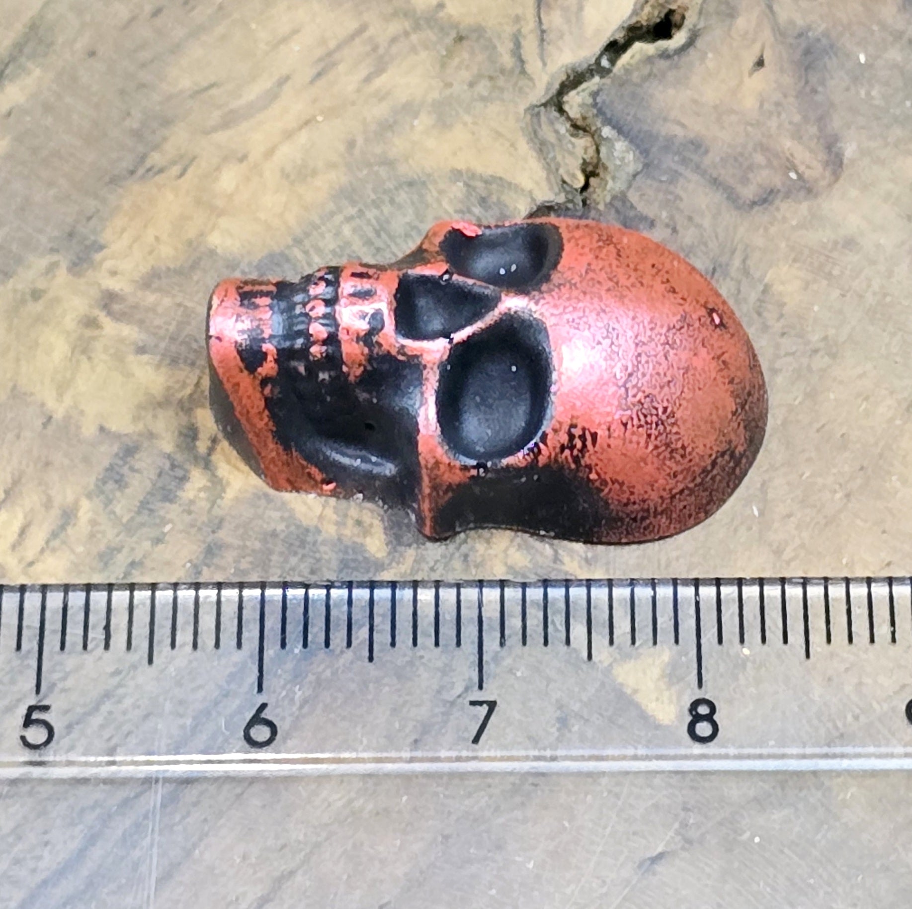 Das Bild zeigt einen Totenkopf-Cabochon in Schwarz mit roter Wachsverzierung