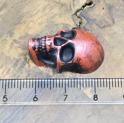 Das Bild zeigt einen Totenkopf-Cabochon in Schwarz mit roter Wachsverzierung