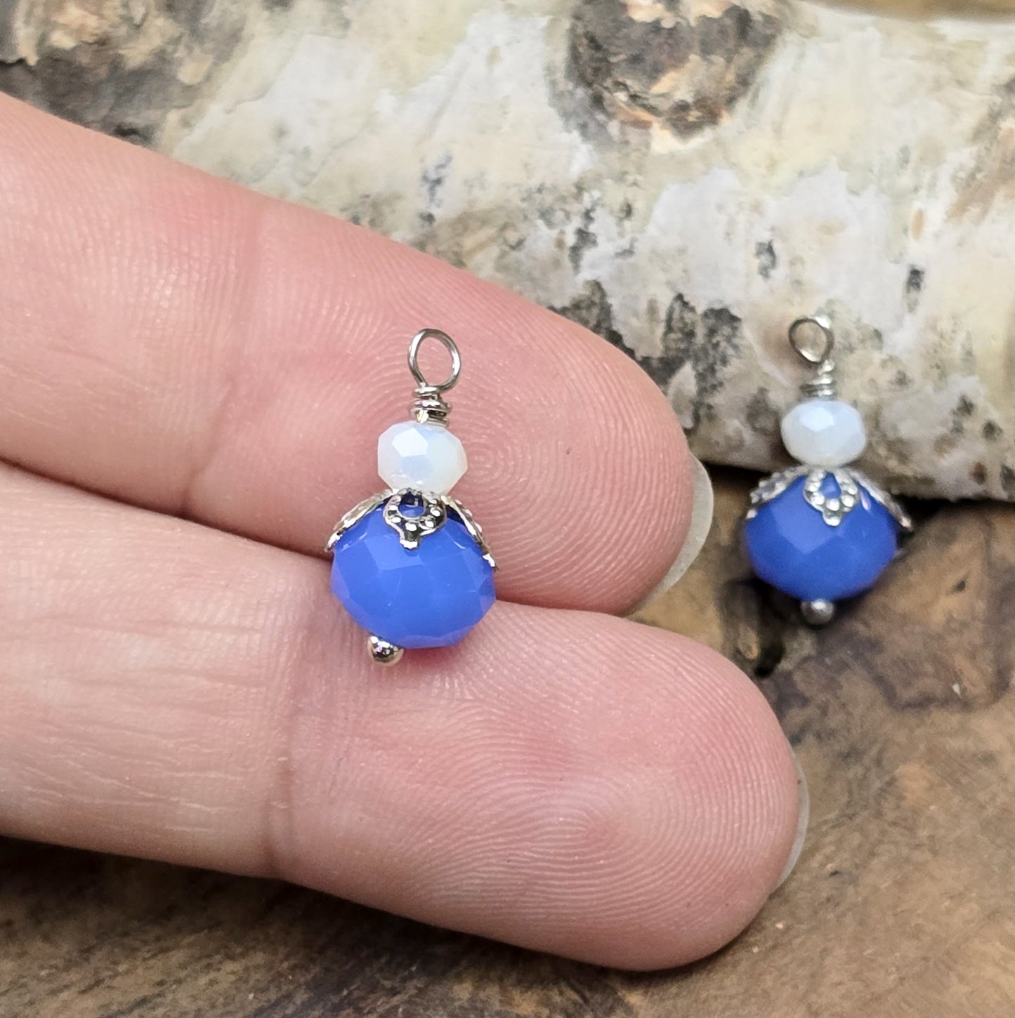 Das Bild zeigt zwei handgefertigte Anhänger mit einer blauen und einer weißen Kristallglasperle, ideal für die individuelle Schmuckherstellung.