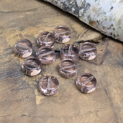 Das Bild zeigt kleine münzförmige Glasperlen in der Farbe Amethyst, für die individuelle Schmuckherstellung.