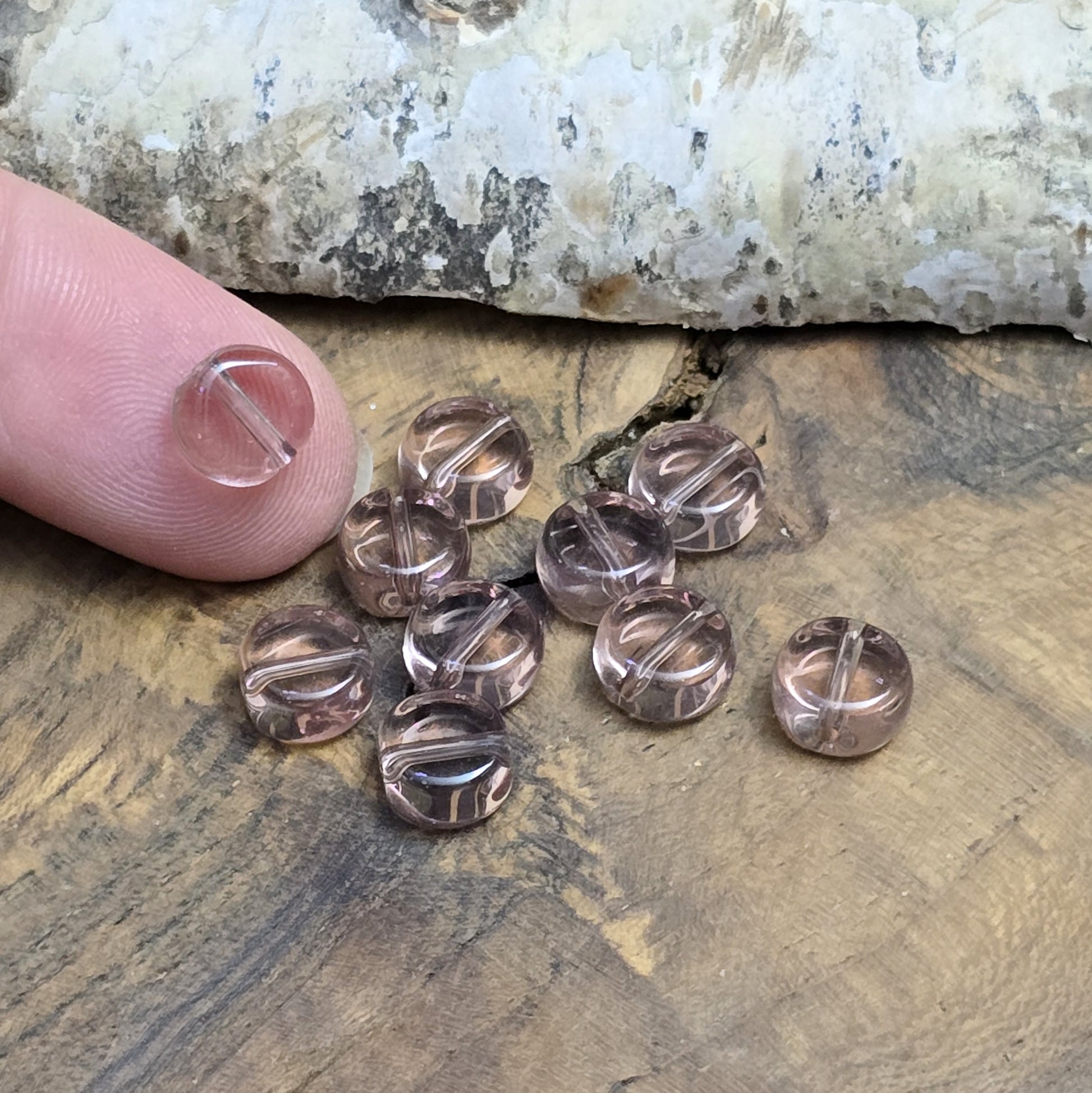 Das Bild zeigt kleine münzförmige Glasperlen in der Farbe Amethyst, für die individuelle Schmuckherstellung.