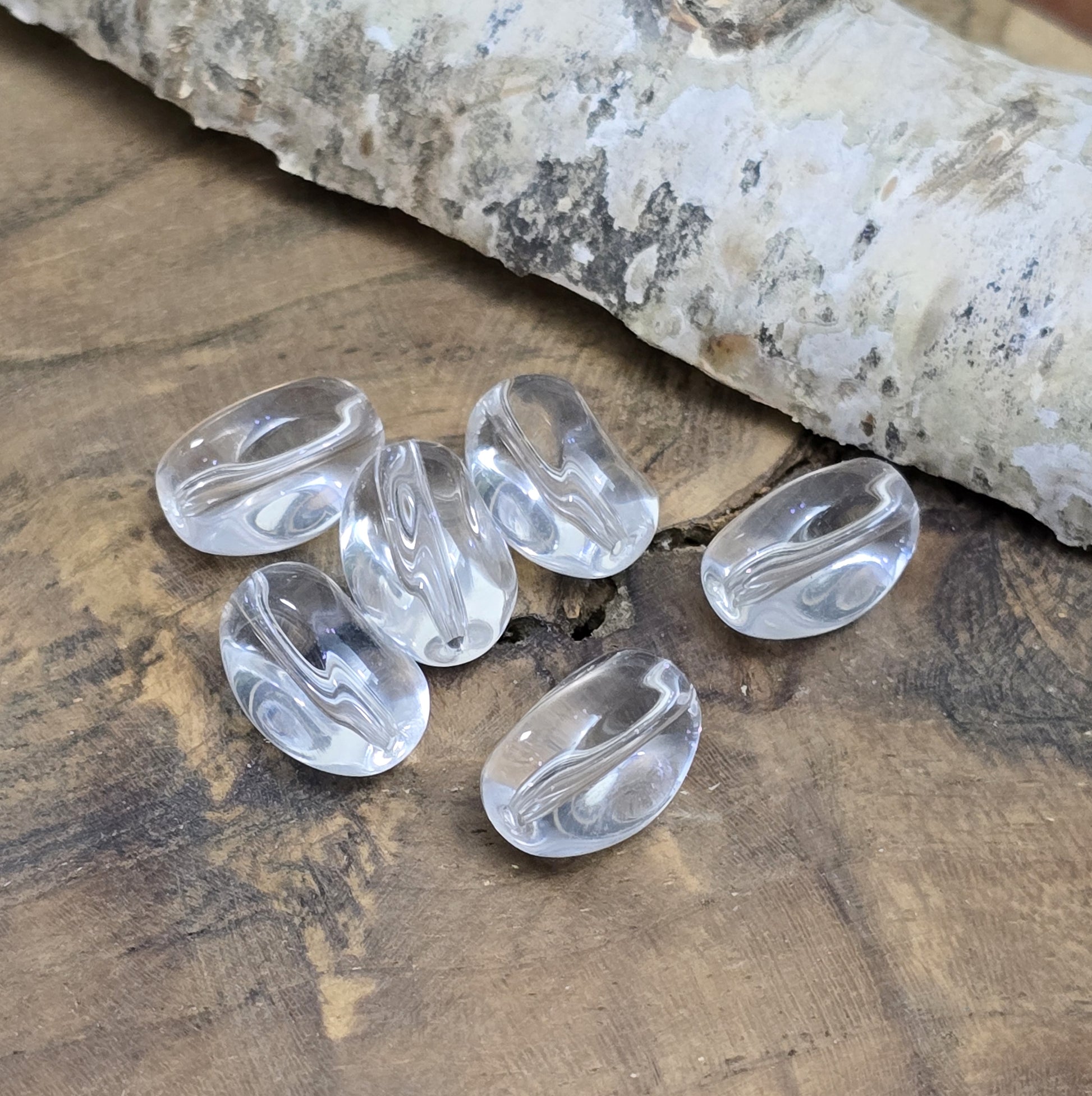 Das Bild zeigt Glasperlen in Nuggetform, farblos transparent. 13mm
