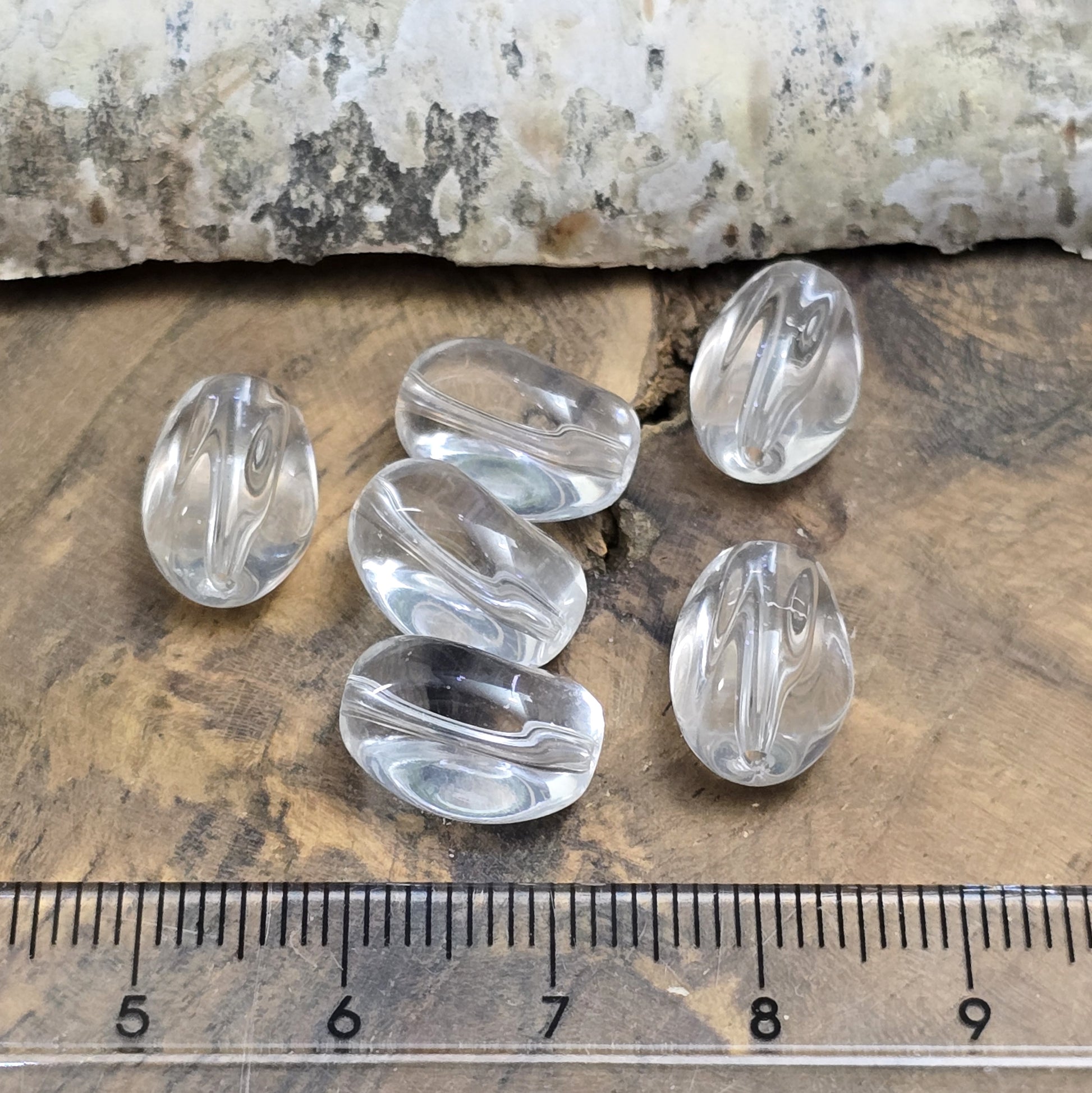 Das Bild zeigt Glasperlen in Nuggetform, farblos transparent. 13mm