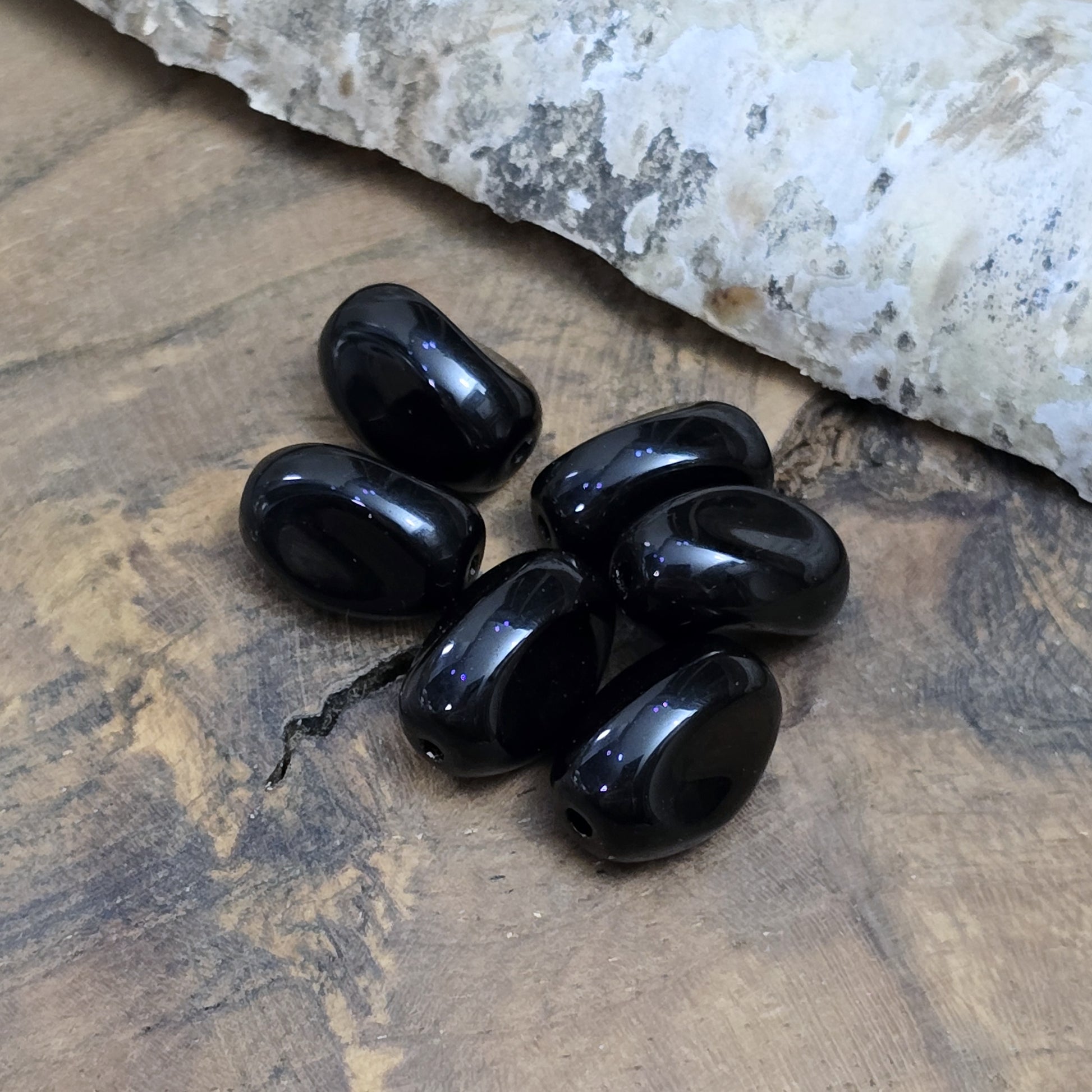 Das Bild zeigt 12 opak schwarze Glasperlen in Nuggetform – 13mm – Für deinen eleganten Schmuck