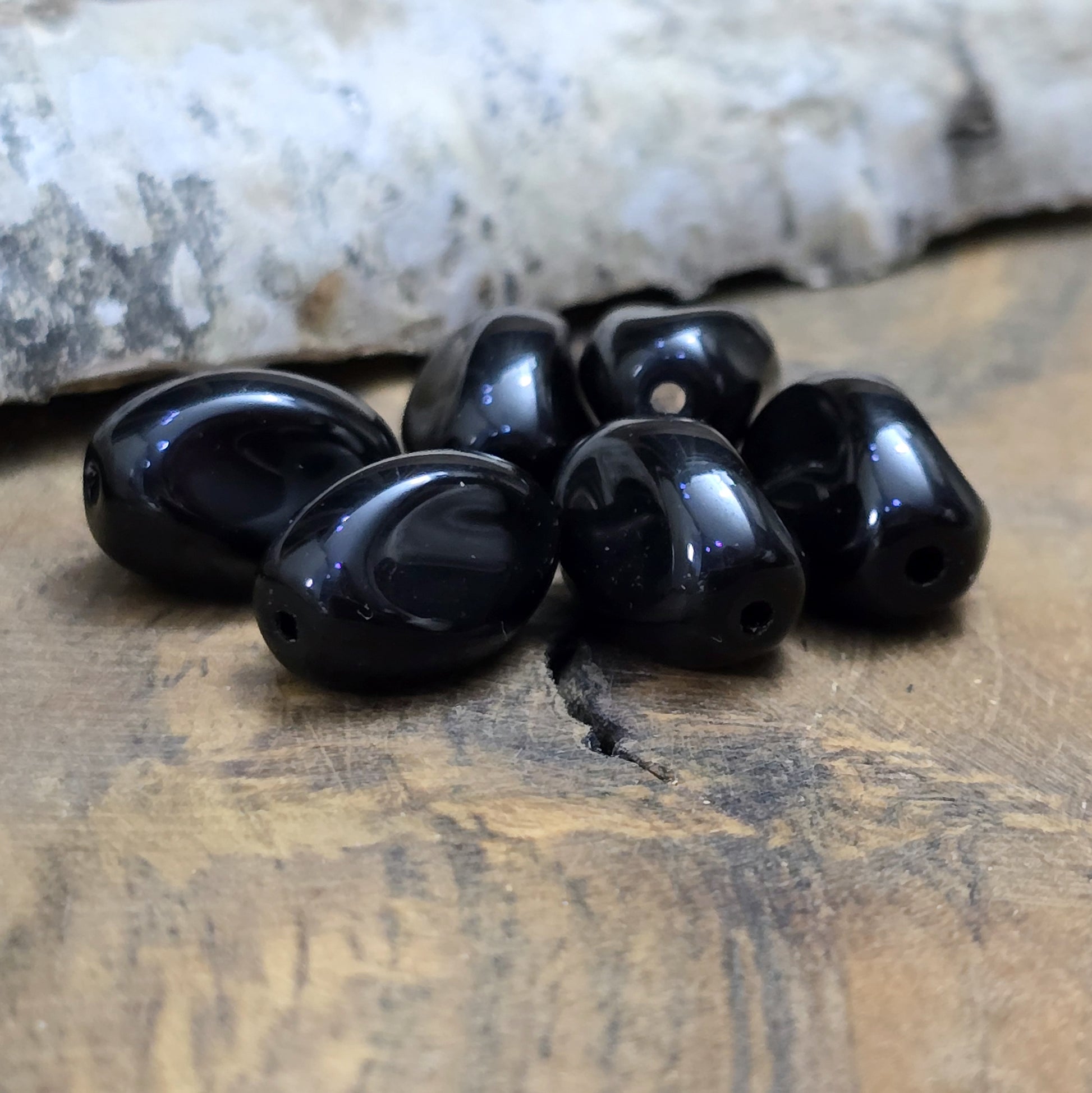 Das Bild zeigt 12 opak schwarze Glasperlen in Nuggetform – 13mm – Für deinen eleganten Schmuck