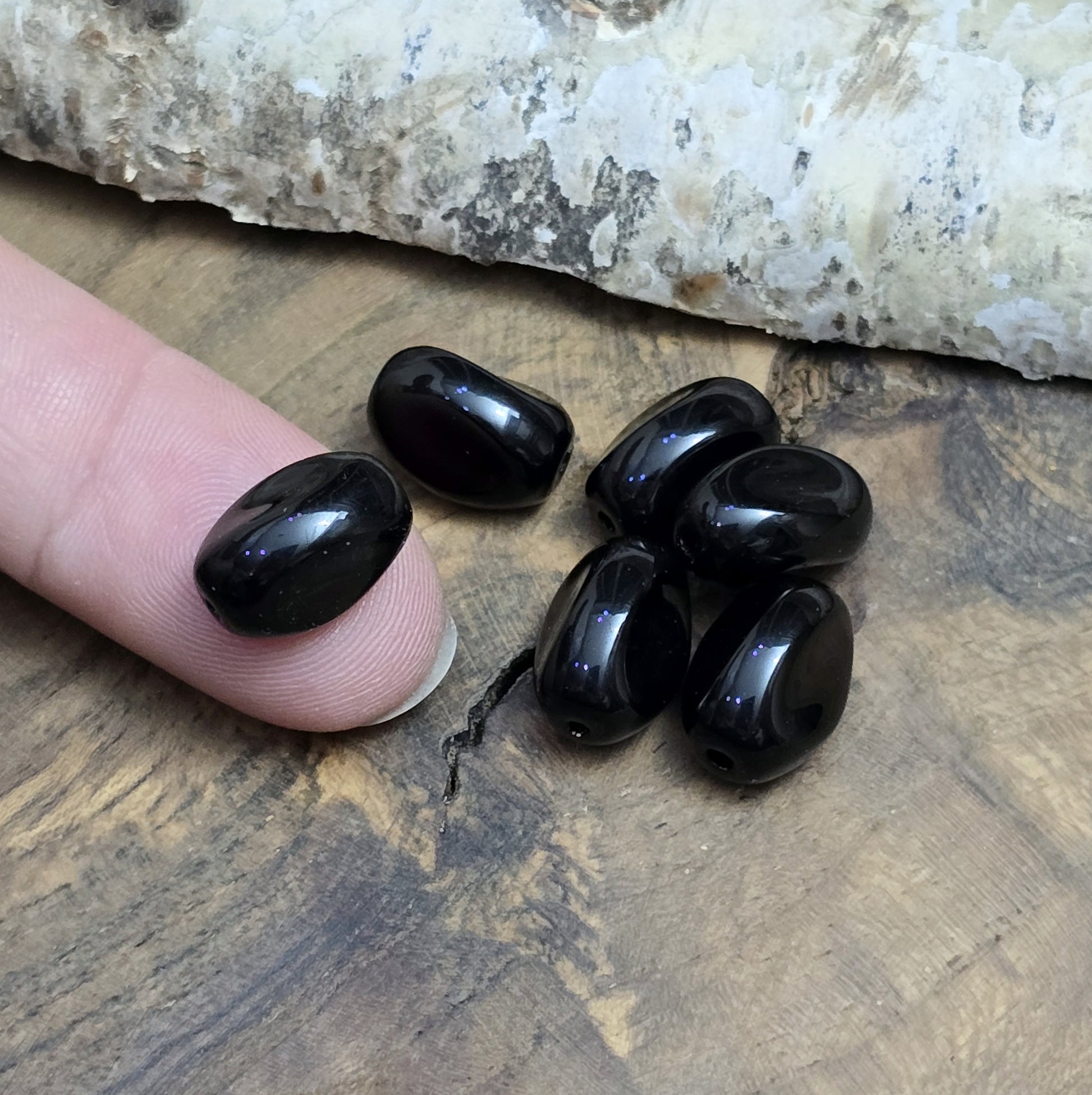 Das Bild zeigt 12 opak schwarze Glasperlen in Nuggetform – 13mm – Für deinen eleganten Schmuck