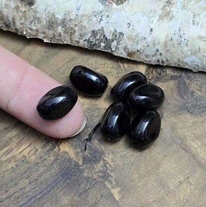 Das Bild zeigt 12 opak schwarze Glasperlen in Nuggetform – 13mm – Für deinen eleganten Schmuck