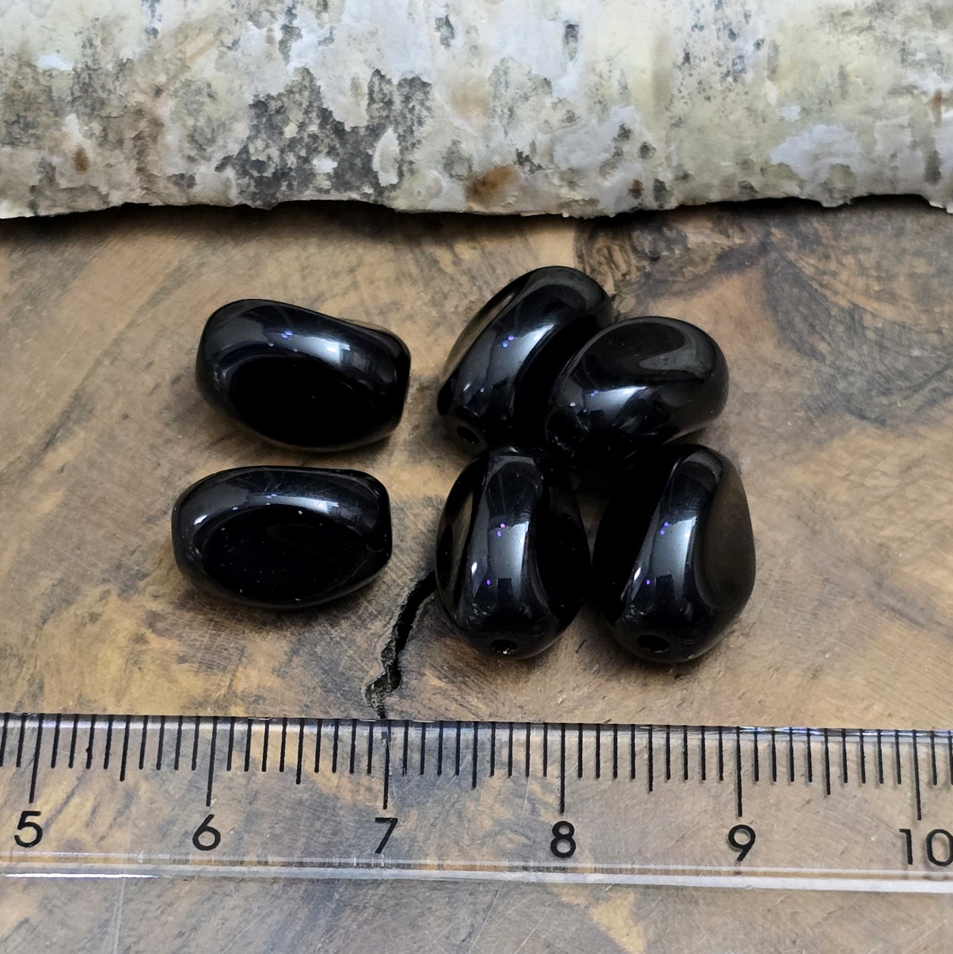 Das Bild zeigt 12 opak schwarze Glasperlen in Nuggetform – 13mm – Für deinen eleganten Schmuck