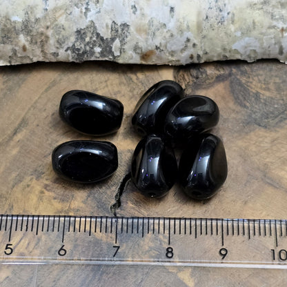 Das Bild zeigt 12 opak schwarze Glasperlen in Nuggetform – 13mm – Für deinen eleganten Schmuck