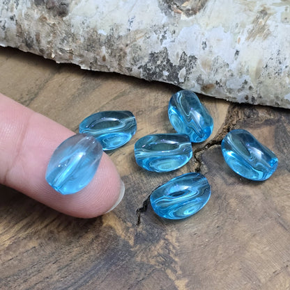Das Bild zeigt 12 transparente Glasperlen in Nuggetform – Aquablau – 13mm – Für strahlend frische Schmuckkreationen