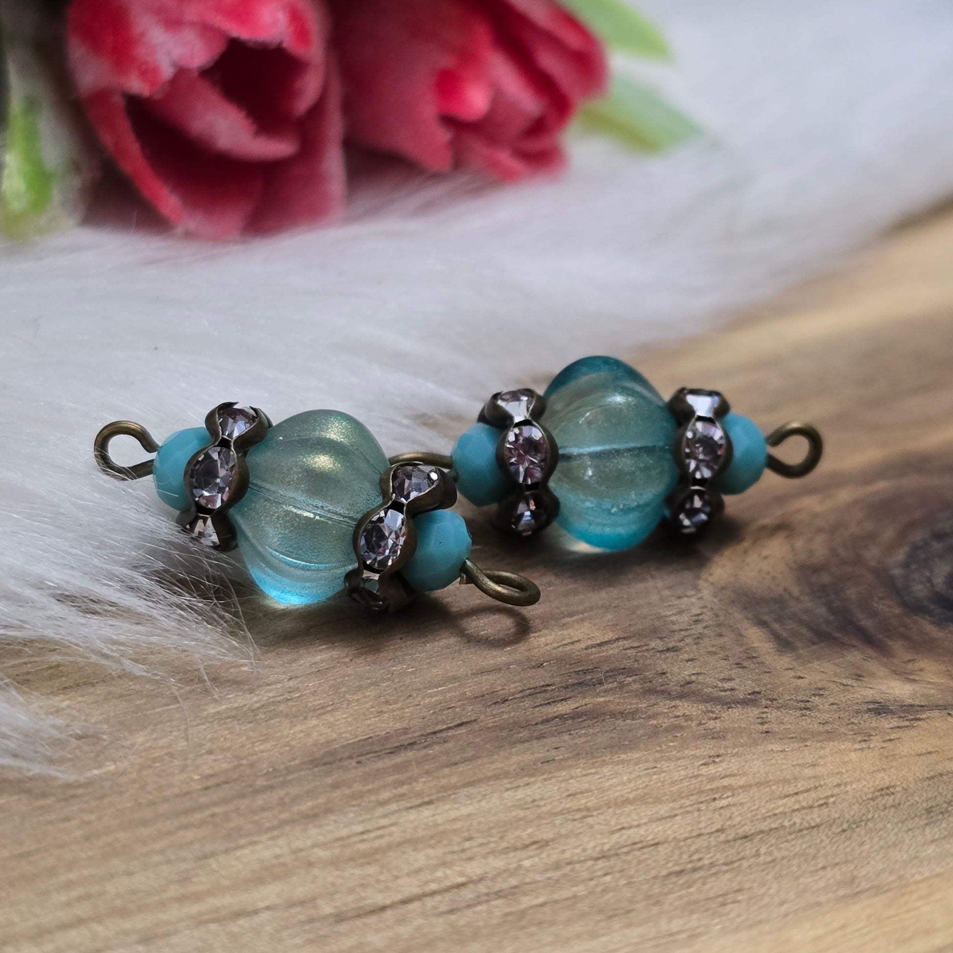 Das Bild zeigt zwei handgefertigte Verbinder mit mintfarbenen Glasperlen in Kürbisform und facettierten Kristallglasperlen. Strassrondelle sorgen für funkelnde Akzente, während antik bronzefarbene Metallelemente dem Design einen eleganten Vintage-Charme verleihen. Die Verbinder sind ca. 25mm groß und ideal für Schmuckkreationen.