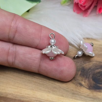 Auf dem Bild sind zwei handgefertigte Anhänger in Form von kleinen Blumen zu sehen. Die Anhänger bestehen aus einer eleganten weißen Acrylblüte und einer zarten rosafarbenen Kristallglasperle. Silberfarbige Metallelemente runden das Design ab und verleihen den Anhängern einen romantischen Charme. Mit einer Größe von ca. 18mm sind sie ideal für die individuelle Schmuckgestaltung, sei es für Ketten, Armbänder oder Ohrringe.