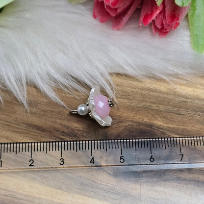 Auf dem Bild sind zwei handgefertigte Anhänger in Form von kleinen Blumen zu sehen. Die Anhänger bestehen aus einer eleganten weißen Acrylblüte und einer zarten rosafarbenen Kristallglasperle. Silberfarbige Metallelemente runden das Design ab und verleihen den Anhängern einen romantischen Charme. Mit einer Größe von ca. 18mm sind sie ideal für die individuelle Schmuckgestaltung, sei es für Ketten, Armbänder oder Ohrringe.