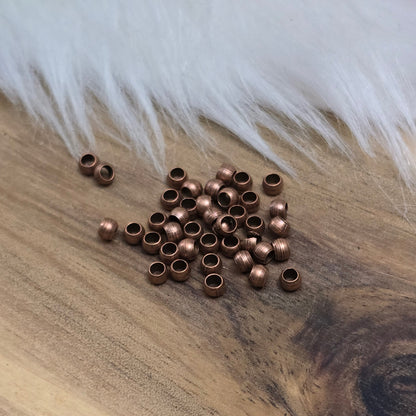 Das Bild zeigt Quetschperlen in Kugelform, antik kupferfarbig mit einem Durchmesser von 2,5mm. Ideal zum Fixieren von Perlen.
