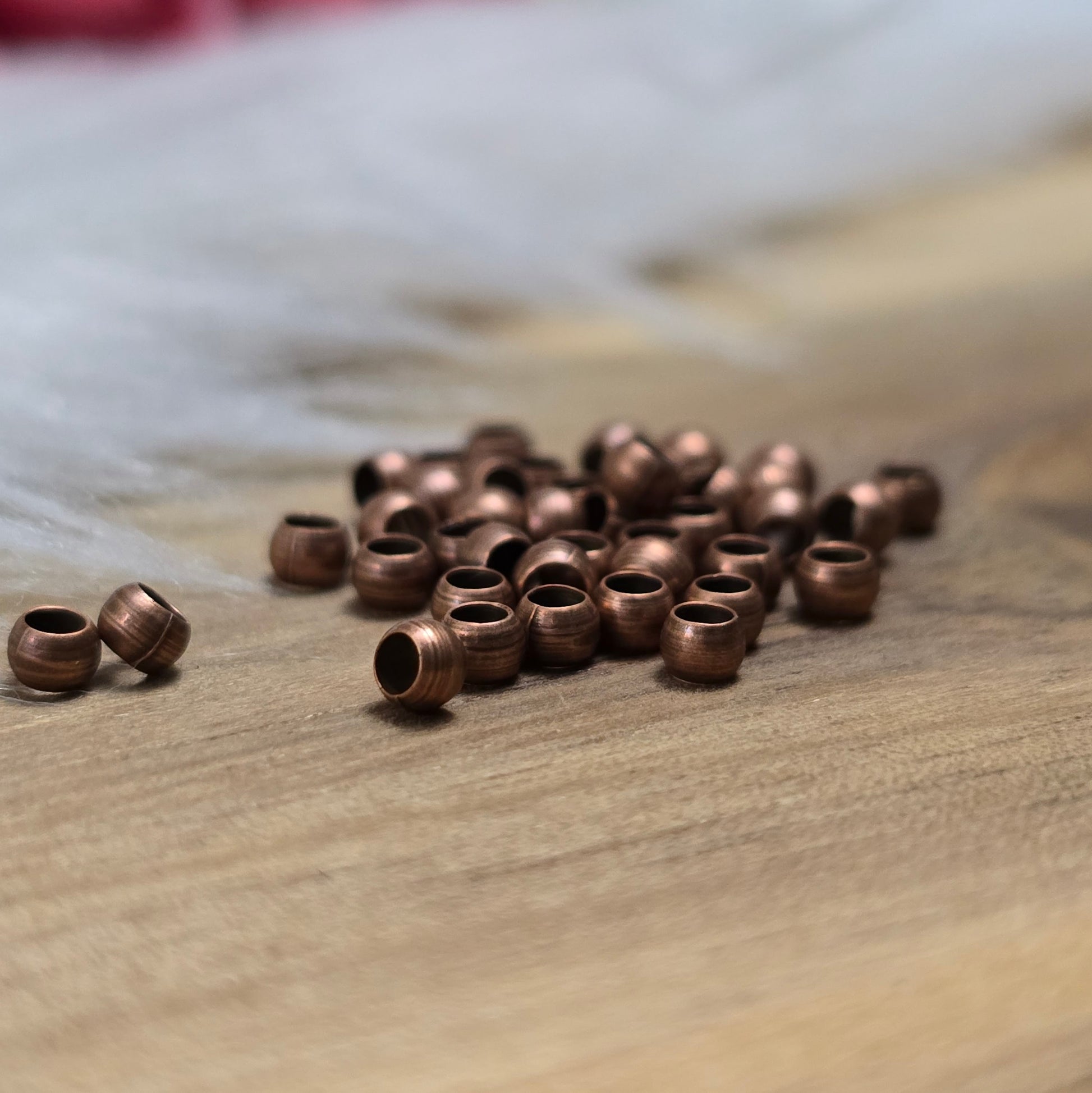 Das Bild zeigt Quetschperlen in Kugelform, antik kupferfarbig mit einem Durchmesser von 2,5mm. Ideal zum Fixieren von Perlen.