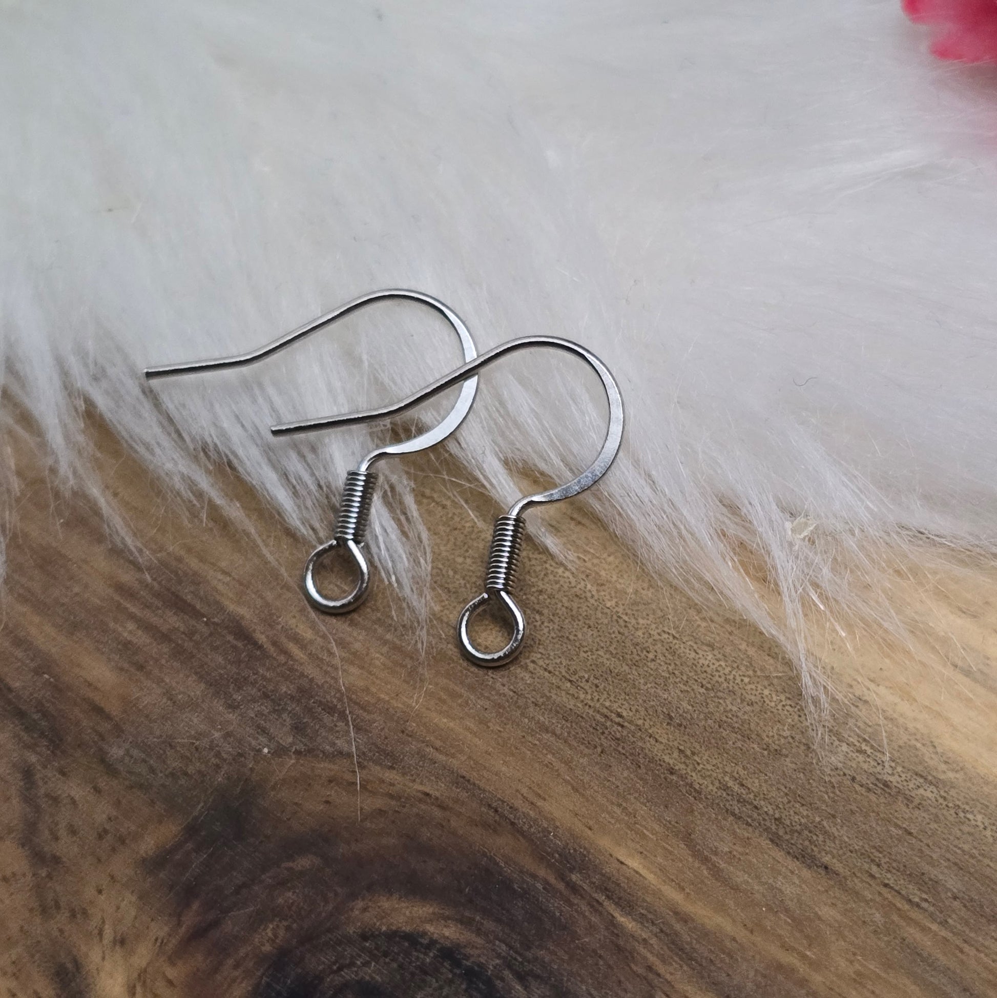 Das Bild zeigt ein Paar French Ohrhaken aus 304 Edelstahl in Silberfarbe. Die Haken haben eine elegante, geschwungene Form mit einer kleinen Öse am unteren Ende, die zur Befestigung von Anhängern oder Perlen dient. Die Oberfläche ist glatt und glänzend, was ihnen ein hochwertiges und modernes Aussehen verleiht. Mit einer Größe von etwa 16 mm sind sie ideal für die Gestaltung individueller Ohrringe.