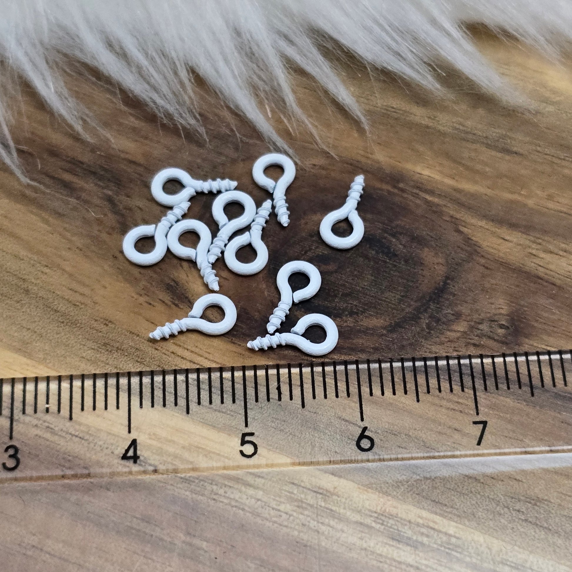 Das Bild zeigt ein Set von 10 farbig lackierten Schraubösen in verschiedenen lebhaften Farben, darunter Hellblau, Grün, Rot, Aqua, Weiß und Rosa. Jede Schrauböse hat die Abmessungen von ca. 8x4mm und ist sorgfältig gestaltet, um eine einfache Anwendung zu ermöglichen. Die Schraubösen sind ideal für das Einschrauben in Materialien wie Holz, Resin oder Acryl, um individuelle Anhänger zu kreieren. Die glänzende Oberfläche der Schraubösen sorgt für einen attraktiven Look, der jedem kreativen Projekt einen farbe