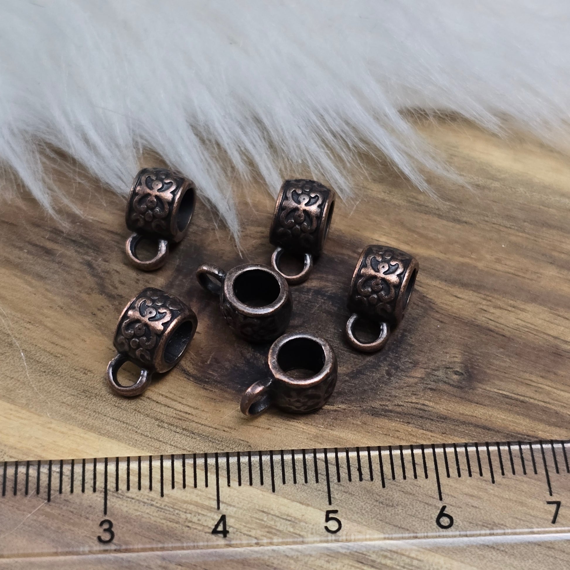 Das Bild zeigt antik kupferfarbige Metallperlen mit Öse.