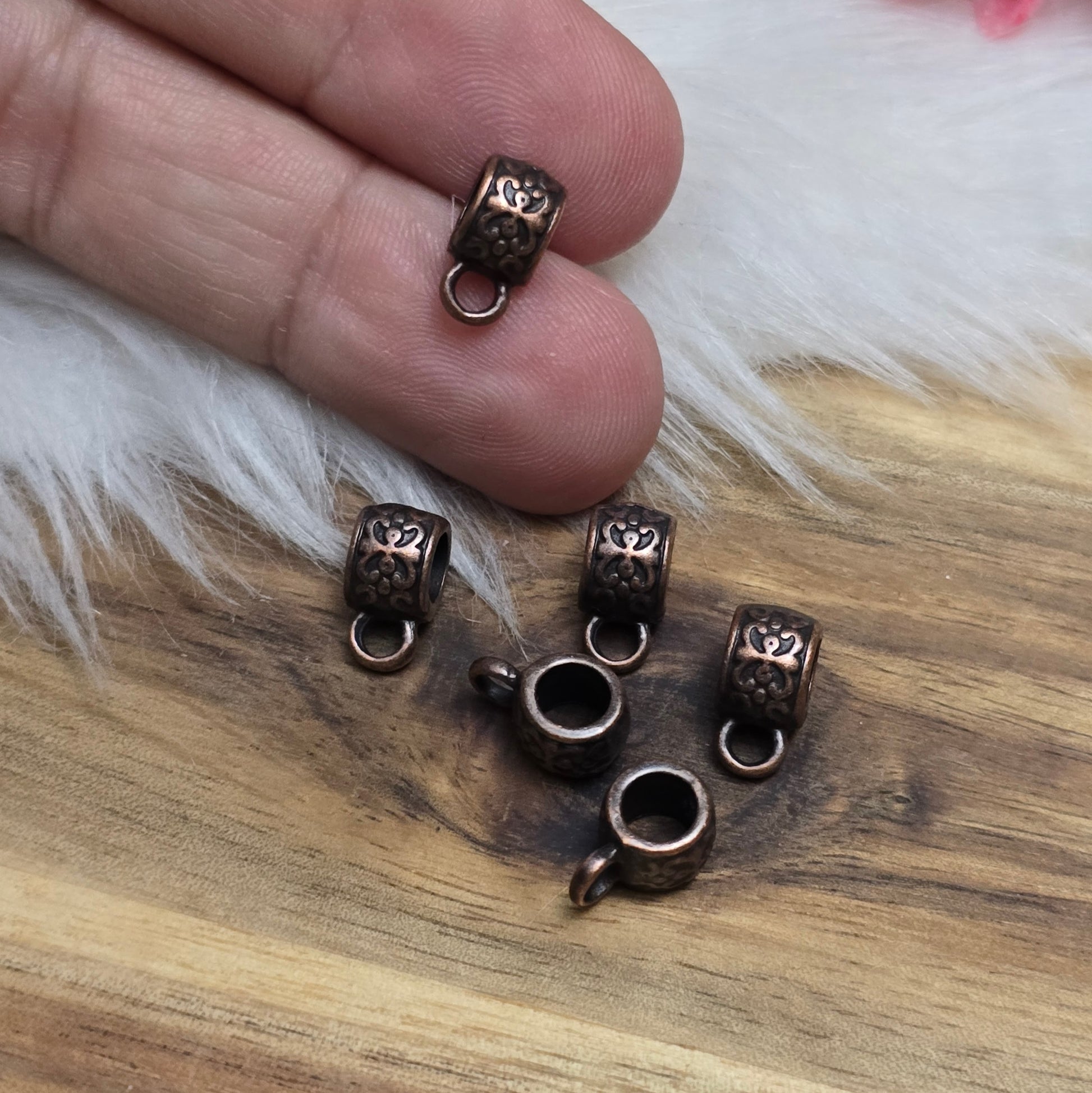 Das Bild zeigt antik kupferfarbige Metallperlen mit Öse.