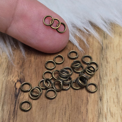 Das Bild zeigt 30 doppelte Binderinge in antikem Bronze-Finish mit 4mm im Durchmesser, ein unverzichtbares Zubehör für die Schmuckherstellung. Durch ihre doppelte Wicklung bieten sie eine besonders stabile und sichere Verbindung, sodass Anhänger, Charms und Verschlüsse zuverlässig befestigt bleiben.
