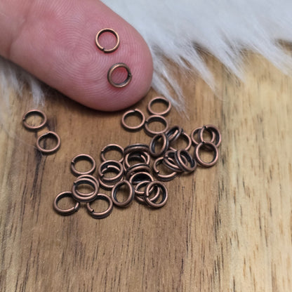 Das Bild zeigt 30 doppelte Binderinge in antikem Kupfer-Finish sind ein unverzichtbares Zubehör für die Schmuckherstellung. Durch ihre doppelte Wicklung bieten sie eine besonders stabile und sichere Verbindung, sodass Anhänger, Charms und Verschlüsse zuverlässig befestigt bleiben.