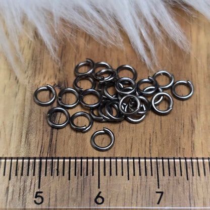 Das Bild zeigt 30 offene Biegeringe in gunmetal black mit 4,2mm Durchmesser, ein unverzichtbares Zubehör für die Schmuckherstellung. Ideal um Charms und Verschlüsse zuverlässig zu befestigen.