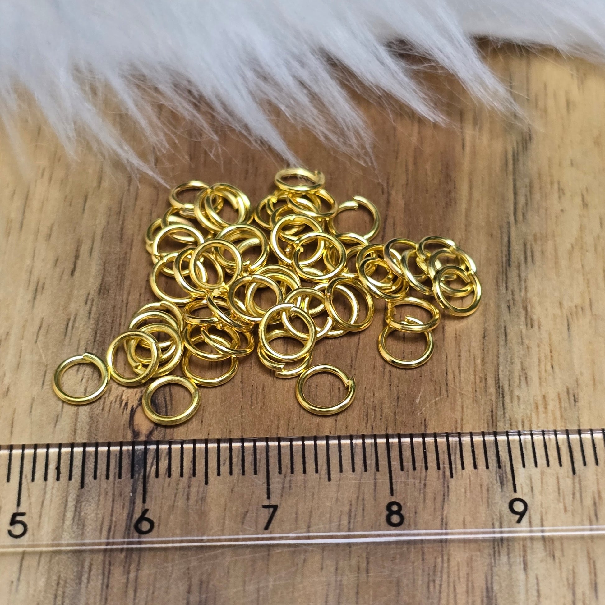 Das Bild zeigt 50 offene Biegeringe in vergoldet mit einem Durchmesser von 5mm, ein unverzichtbares Zubehör für die Schmuckherstellung. Ideal um Charms und Verschlüsse zuverlässig zu befestigen.