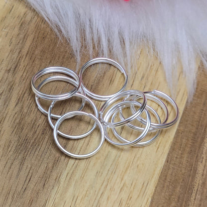 Das Bild zeigt 10 doppelte Binderinge in versilbert mit einem Durchmesser von 12mm. Die Verbindungsringe sind ein unverzichtbares Zubehör für die Schmuckherstellung. Durch ihre doppelte Wicklung bieten sie eine besonders stabile und sichere Verbindung, sodass Anhänger, Charms und Verschlüsse zuverlässig befestigt bleiben.