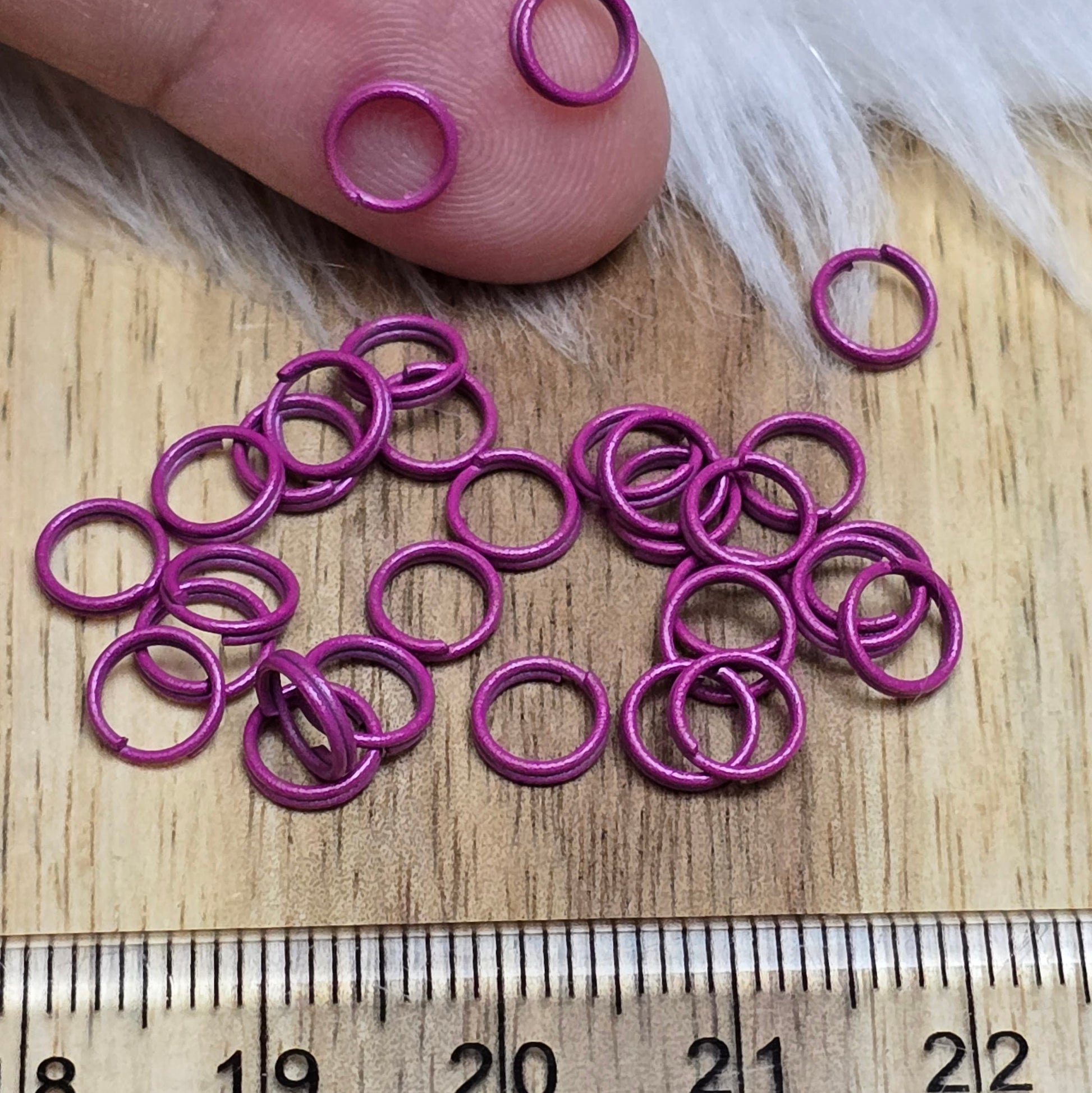 Das Bild zeigt 30 doppelte Binderinge in der Farbe Magenta mit einem Durchmesser von 6mm. Die Verbindungsringe sind ein unverzichtbares Zubehör für die Schmuckherstellung. Durch ihre doppelte Wicklung bieten sie eine besonders stabile und sichere Verbindung, sodass Anhänger, Charms und Verschlüsse zuverlässig befestigt bleiben.
