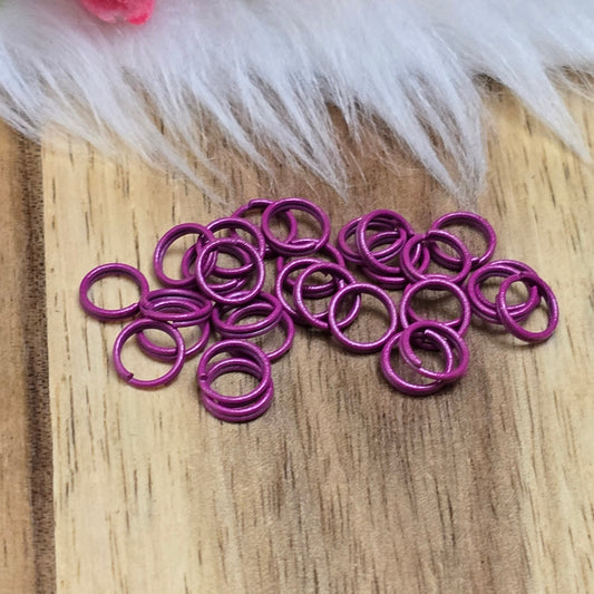 Das Bild zeigt 30 doppelte Binderinge in der Farbe Magenta mit einem Durchmesser von 6mm. Die Verbindungsringe sind ein unverzichtbares Zubehör für die Schmuckherstellung. Durch ihre doppelte Wicklung bieten sie eine besonders stabile und sichere Verbindung, sodass Anhänger, Charms und Verschlüsse zuverlässig befestigt bleiben.