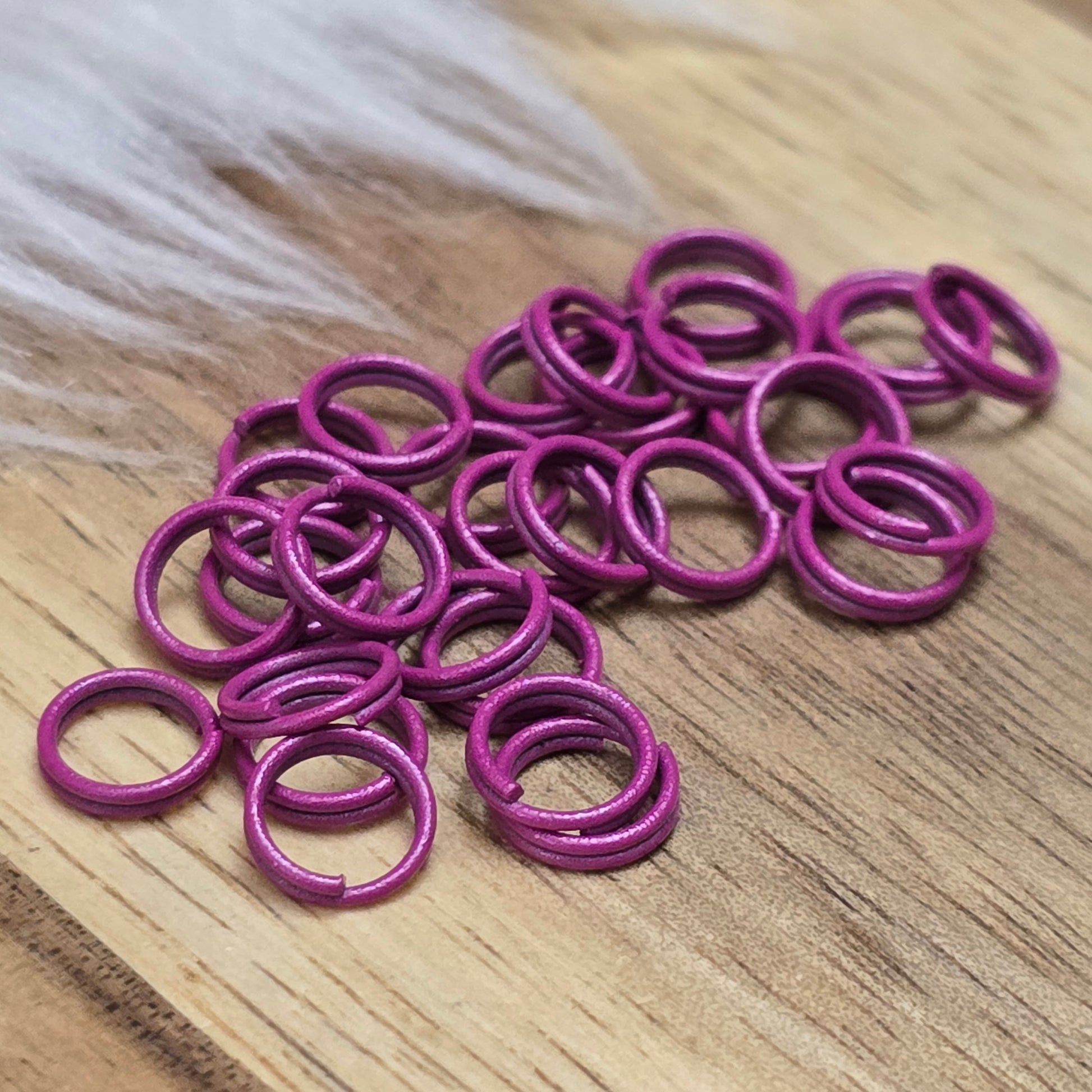 Das Bild zeigt 30 doppelte Binderinge in der Farbe Magenta mit einem Durchmesser von 6mm. Die Verbindungsringe sind ein unverzichtbares Zubehör für die Schmuckherstellung. Durch ihre doppelte Wicklung bieten sie eine besonders stabile und sichere Verbindung, sodass Anhänger, Charms und Verschlüsse zuverlässig befestigt bleiben.