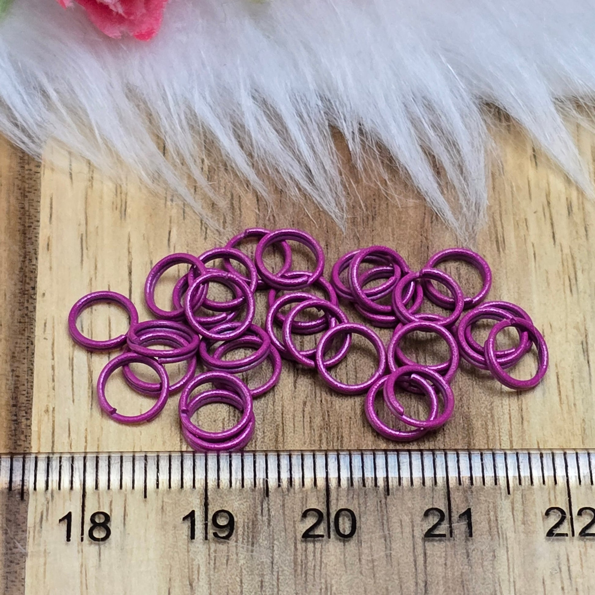 Das Bild zeigt 30 doppelte Binderinge in der Farbe Magenta mit einem Durchmesser von 6mm. Die Verbindungsringe sind ein unverzichtbares Zubehör für die Schmuckherstellung. Durch ihre doppelte Wicklung bieten sie eine besonders stabile und sichere Verbindung, sodass Anhänger, Charms und Verschlüsse zuverlässig befestigt bleiben.