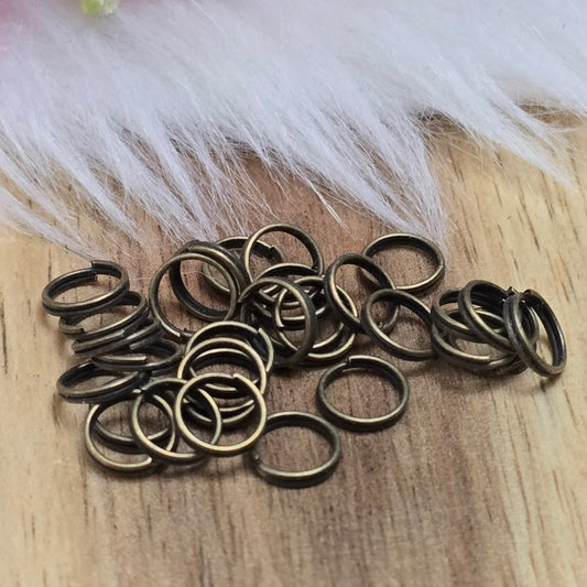 Das Bild zeigt 30 doppelte Binderinge in antikem Bronze-Finish mit 6mm Durchmesser. Die Verbindungsringe sind ein unverzichtbares Zubehör für die Schmuckherstellung. Durch ihre doppelte Wicklung bieten sie eine besonders stabile und sichere Verbindung, sodass Anhänger, Charms und Verschlüsse zuverlässig befestigt bleiben.
