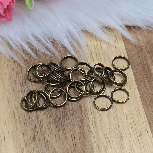 Das Bild zeigt 30 doppelte Binderinge in antik bronzefarbig mit einem Durchmesser von 7mm. Die Verbindungsringe sind ein unverzichtbares Zubehör für die Schmuckherstellung. Durch ihre doppelte Wicklung bieten sie eine besonders stabile und sichere Verbindung, sodass Anhänger, Charms und Verschlüsse zuverlässig befestigt bleiben.