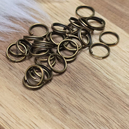 Das Bild zeigt 30 doppelte Binderinge in antik bronzefarbig mit einem Durchmesser von 7mm. Die Verbindungsringe sind ein unverzichtbares Zubehör für die Schmuckherstellung. Durch ihre doppelte Wicklung bieten sie eine besonders stabile und sichere Verbindung, sodass Anhänger, Charms und Verschlüsse zuverlässig befestigt bleiben.